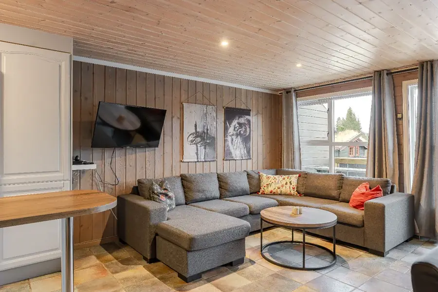 Vardagsrum med stor soffa och TV i stuga Bakkebygrenda 1B, Trysil